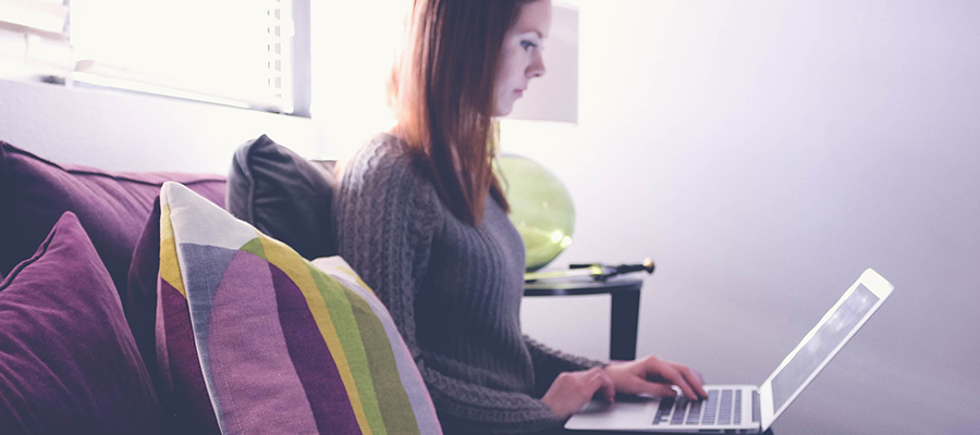 Sara sitting in conference room Cube, working on her laptop.