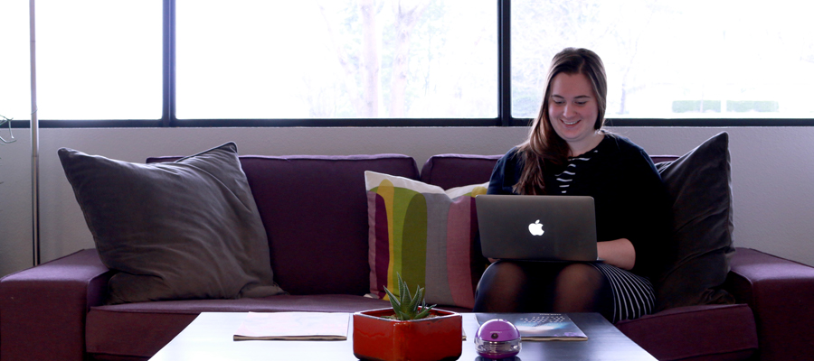Amanda, an Envano digital storyteller, sitting on the couch typing on her MacBook.