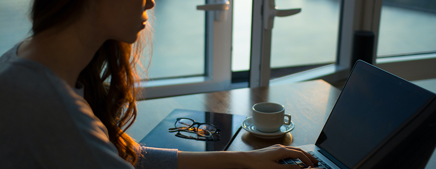 A woman writing an article on a laptop.